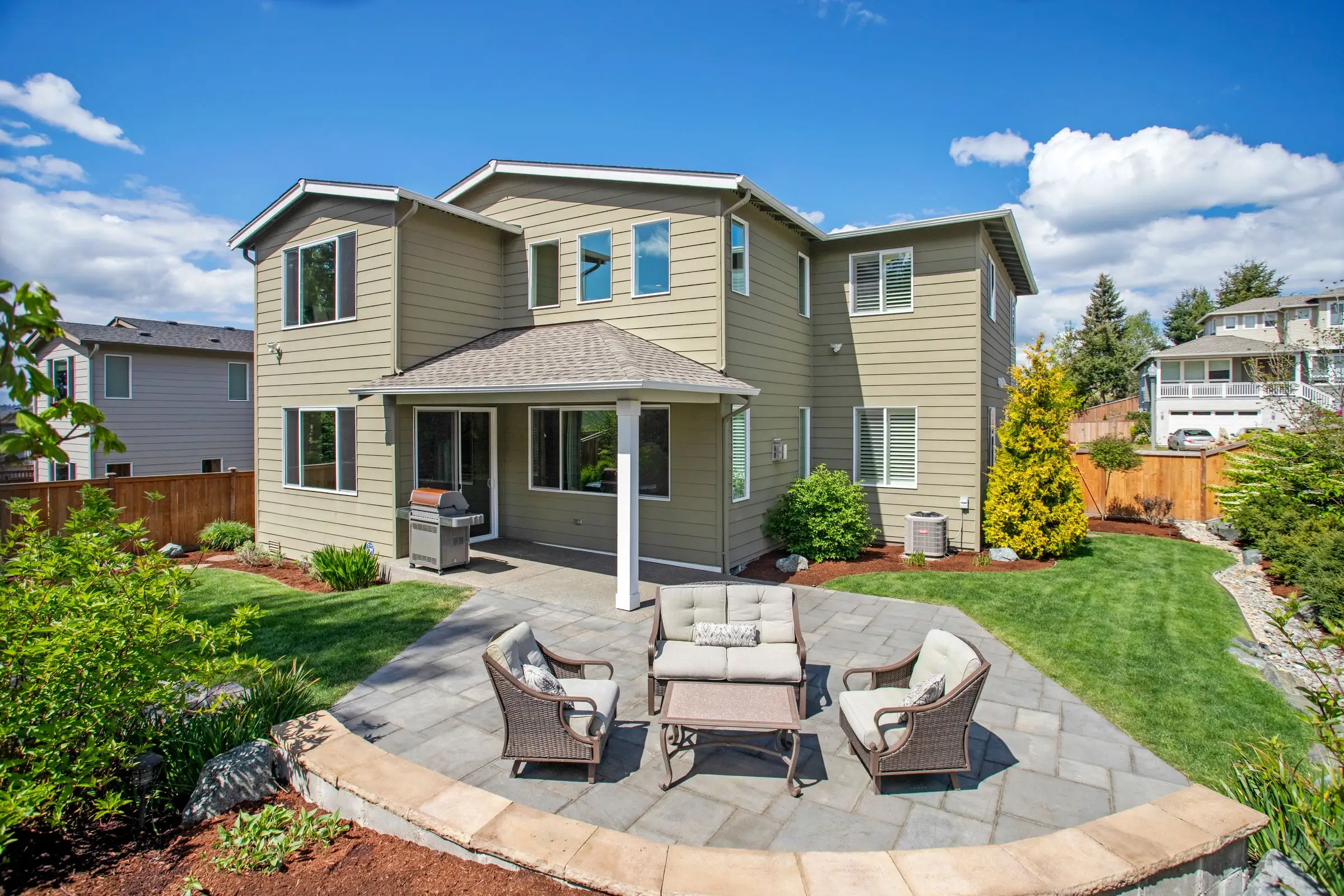 Suburban back yard with a paved seating area and planted borders
