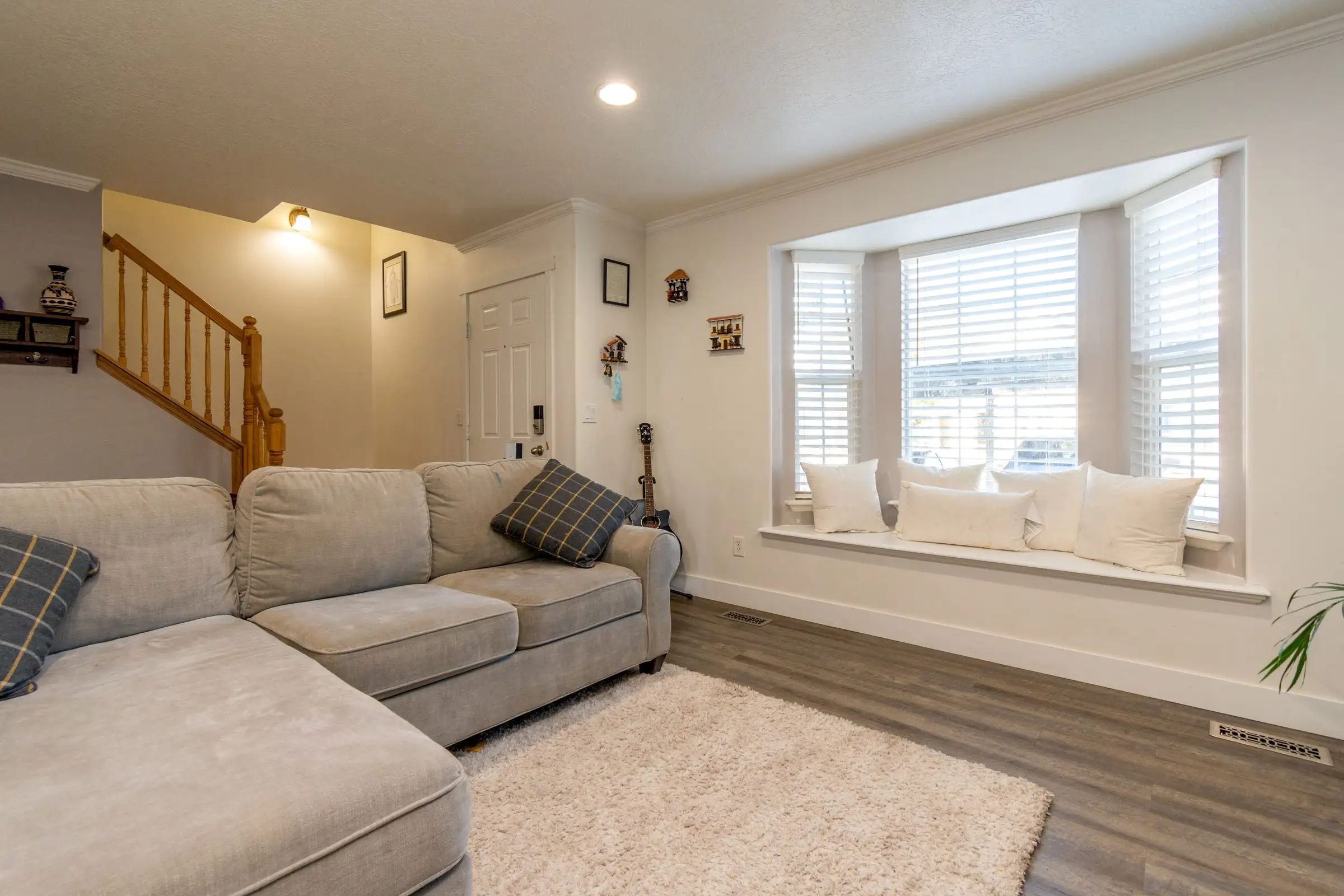 Bay window filling one wall of a plain living room with daylight