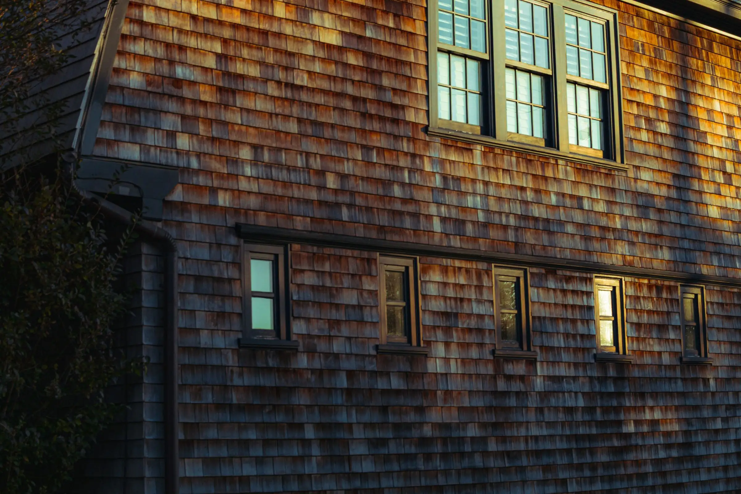 Cedar shingle facade of a coastal house lit by evening sun