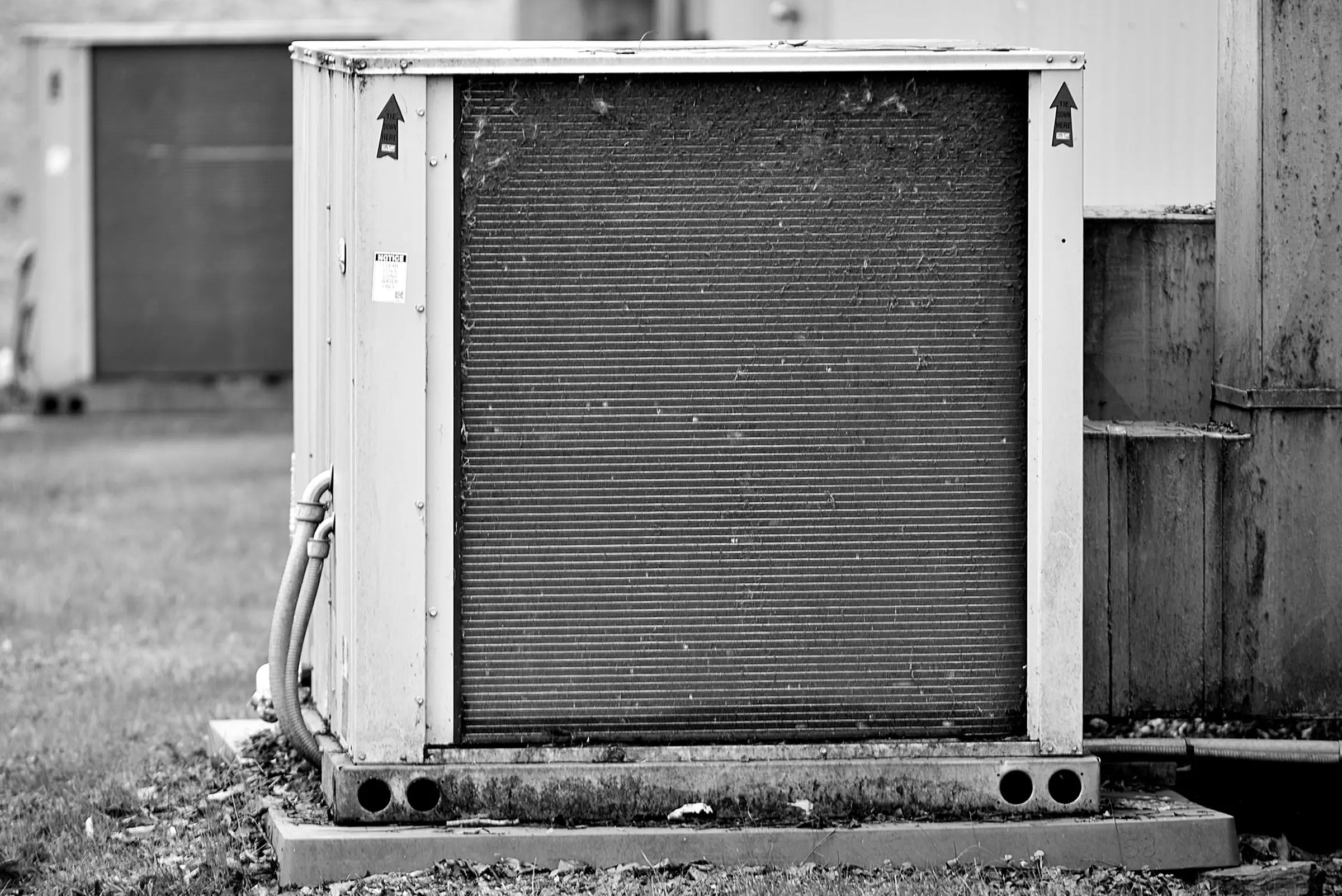Weathered outdoor condenser unit on a concrete pad, coil fins dulled by years of service