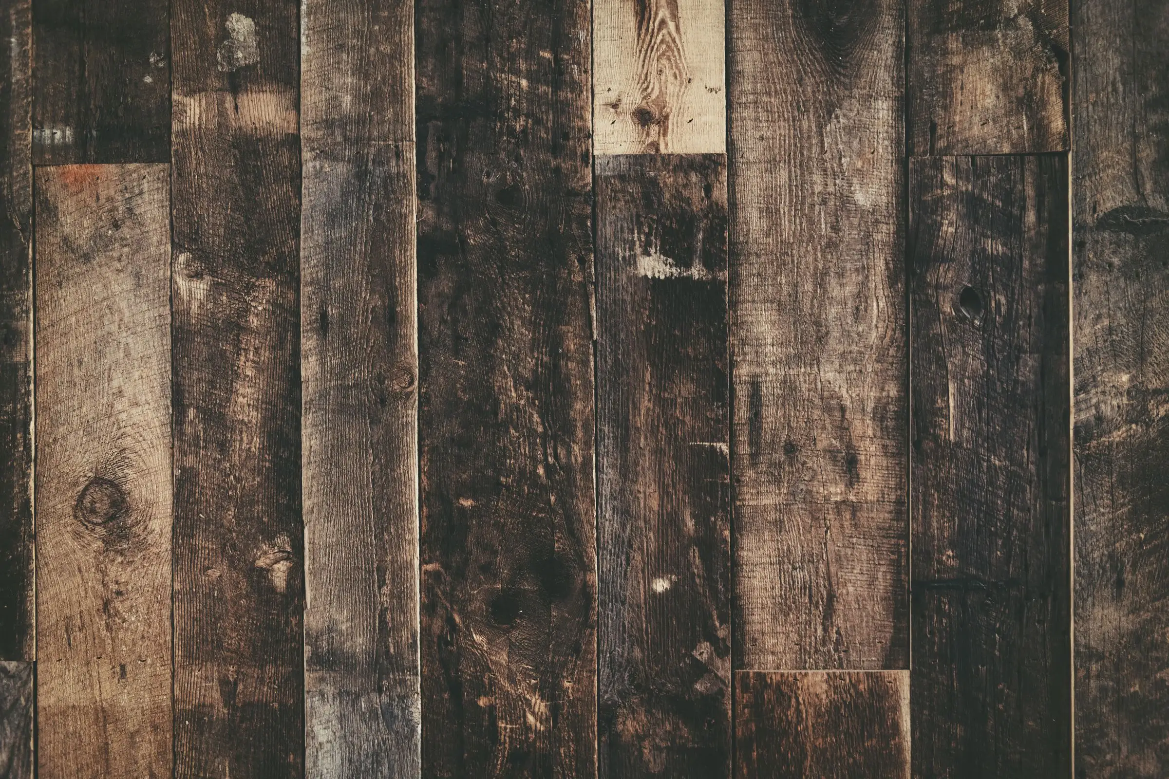 Weathered floor planks meeting end to end, grain raised with age