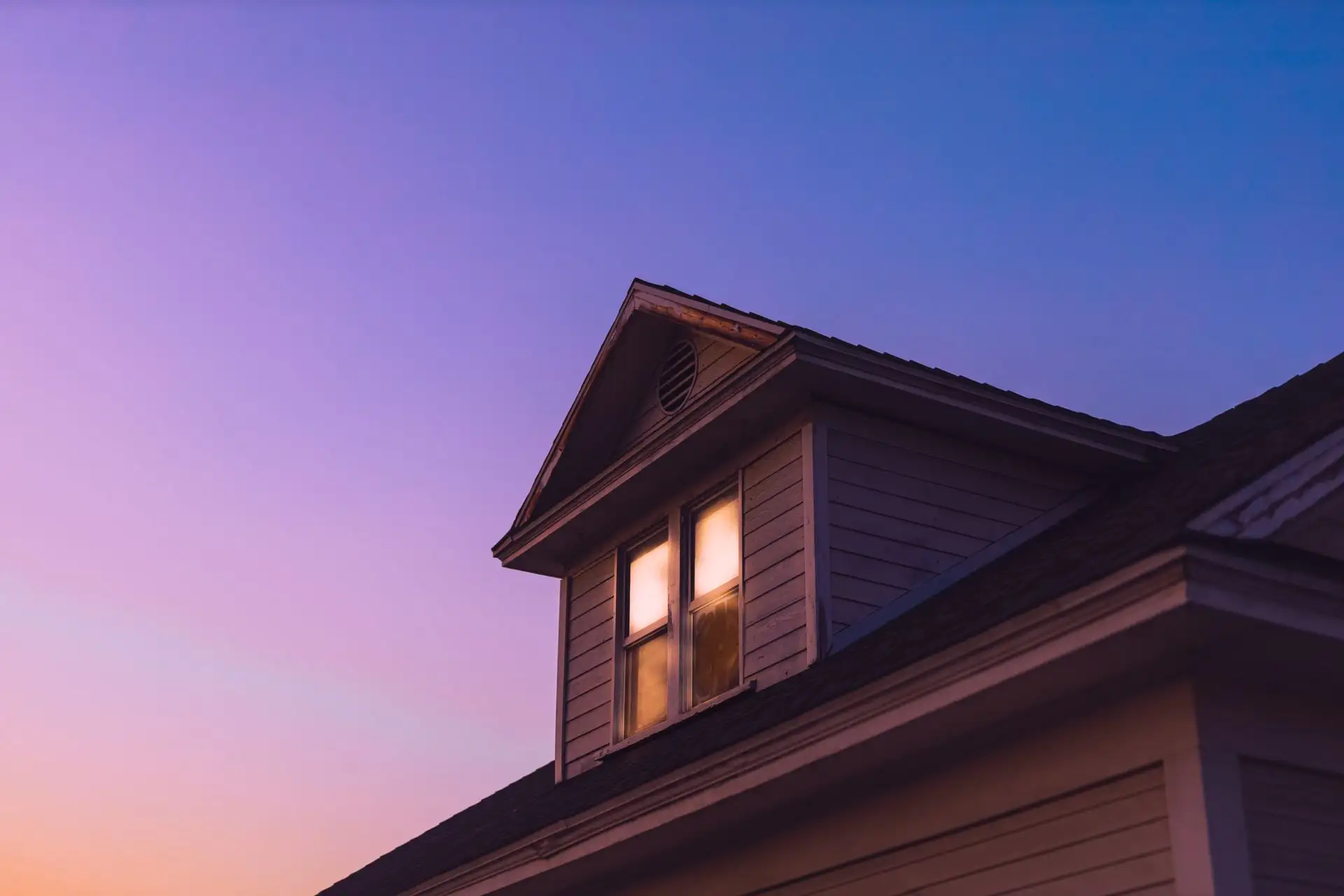Dormer window glowing at dusk under a purple sky