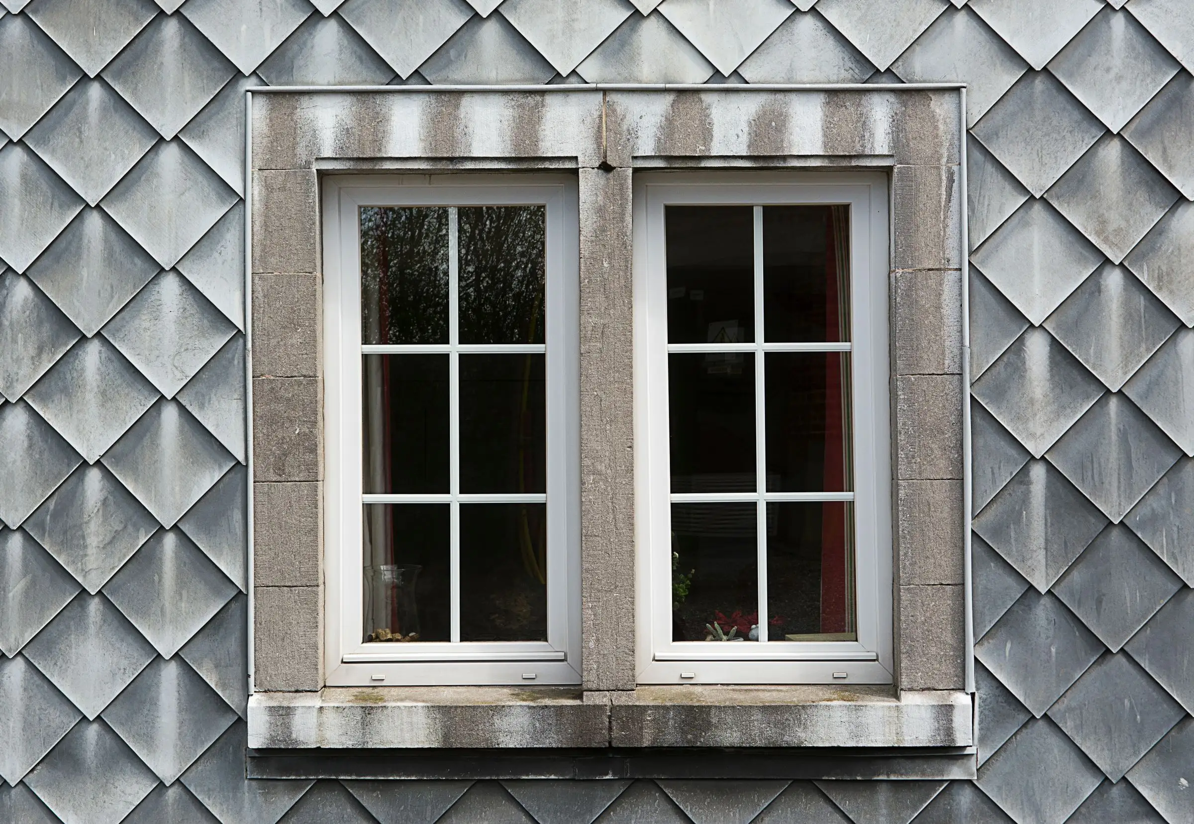 Pair of white-framed windows set into a weathered shingle facade