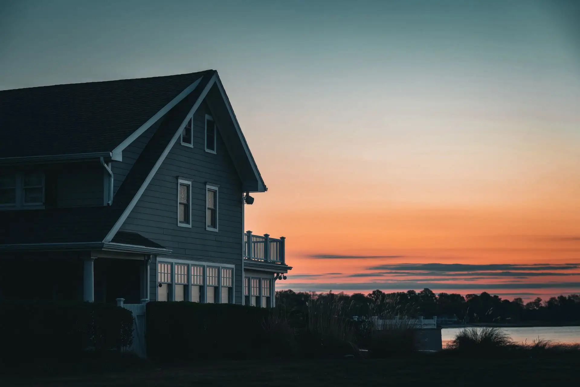 American house silhouetted against an orange and teal sunset sky