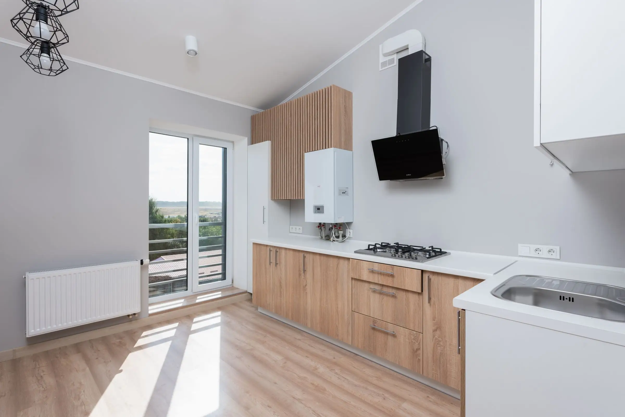 Empty fitted kitchen with plain cabinets and daylight from tall windows