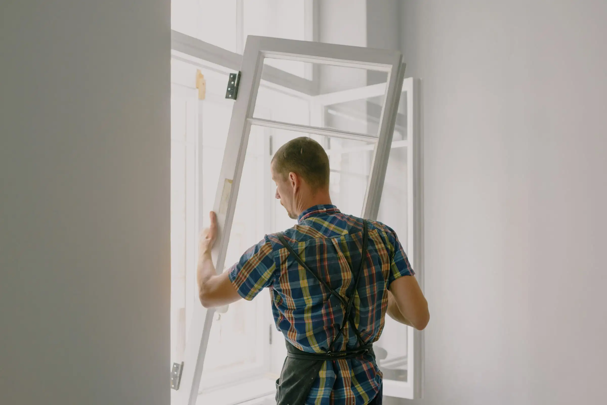 Fitter mounting a window frame into a rough opening during a renovation