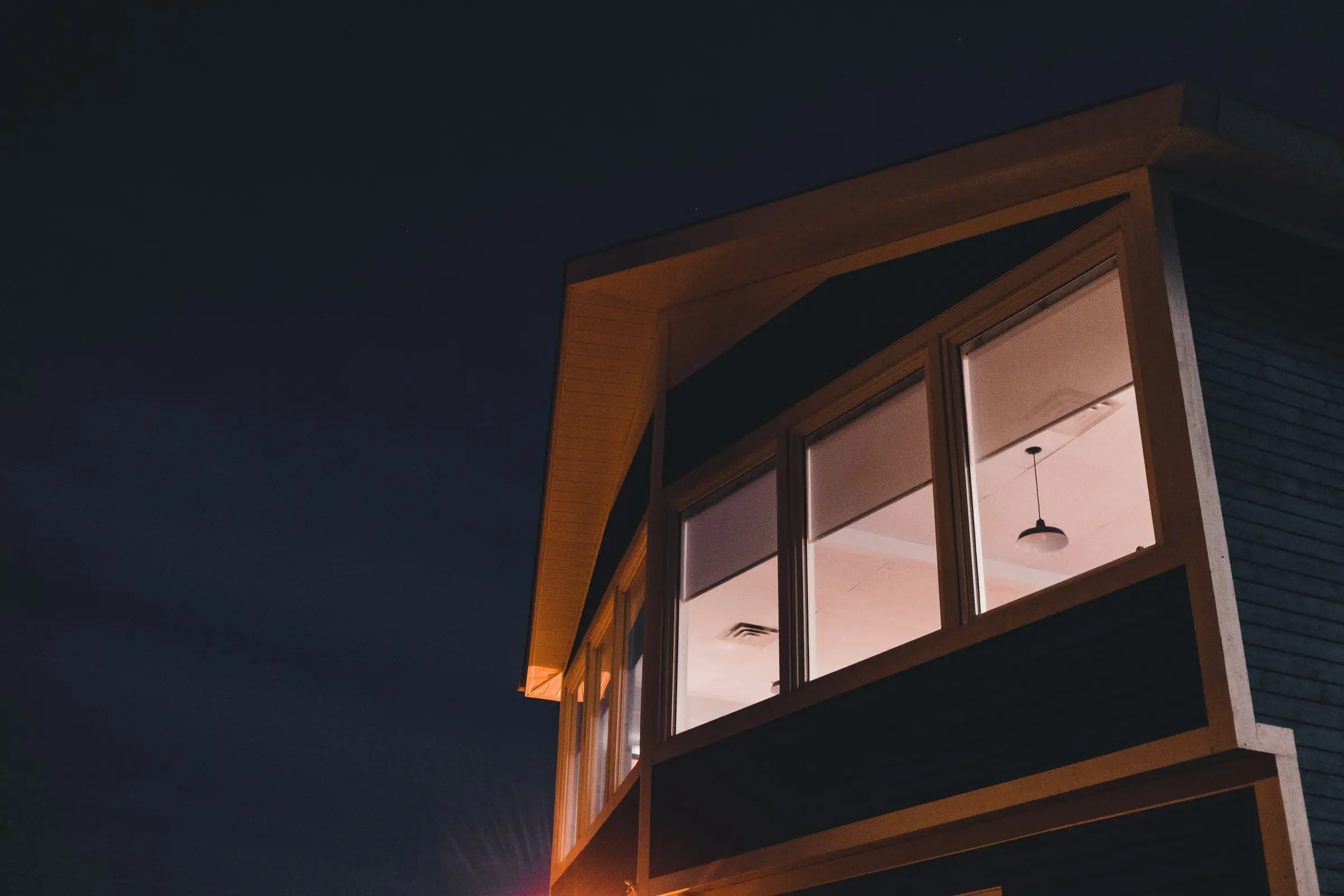 Modern house with large windows glowing warmly against the night