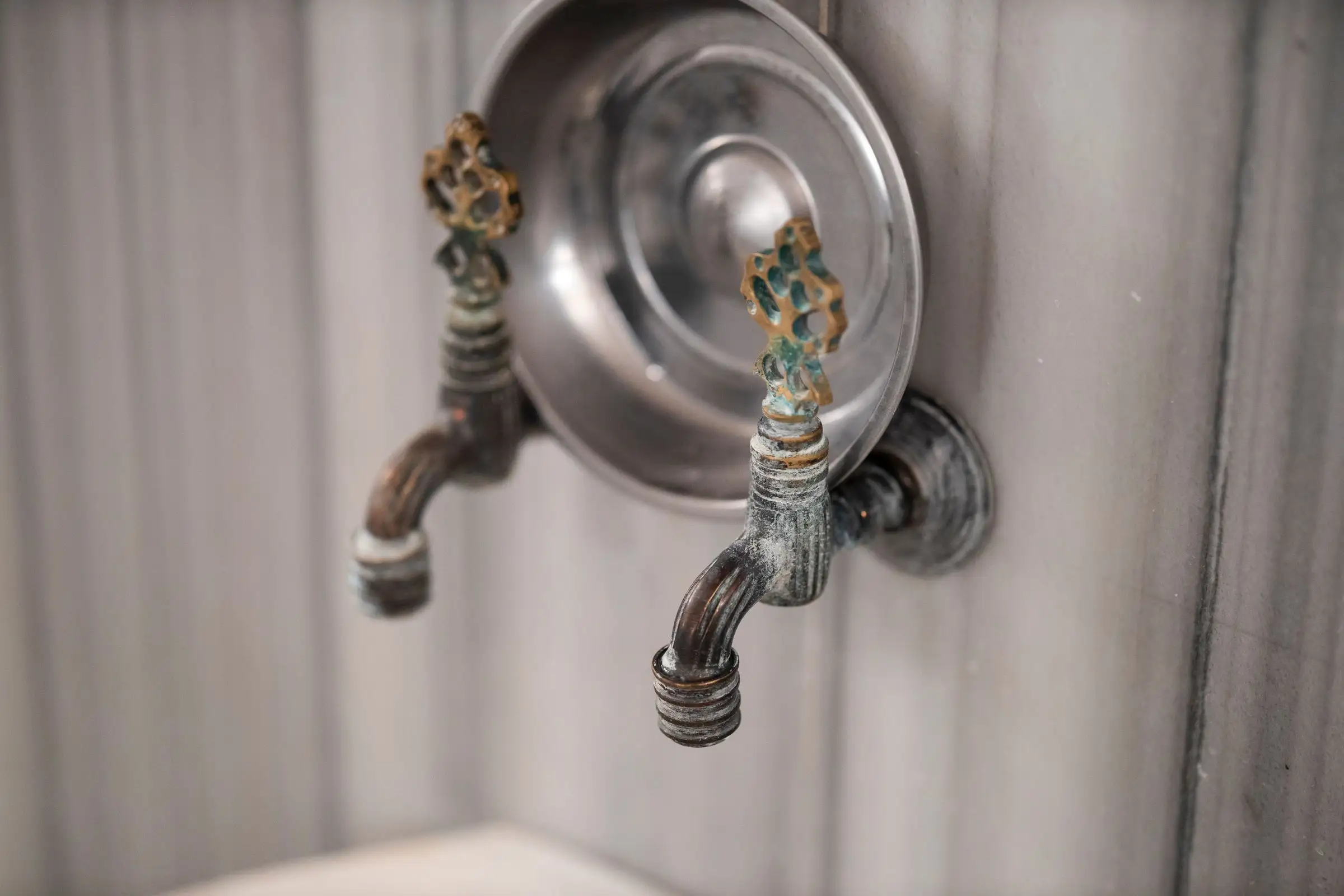 Row of aged brass faucets against stone