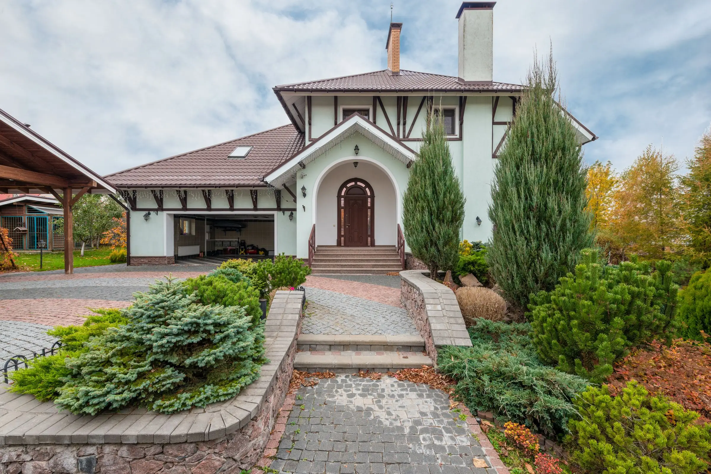 Suburban house front with structured planting beds and a paved driveway