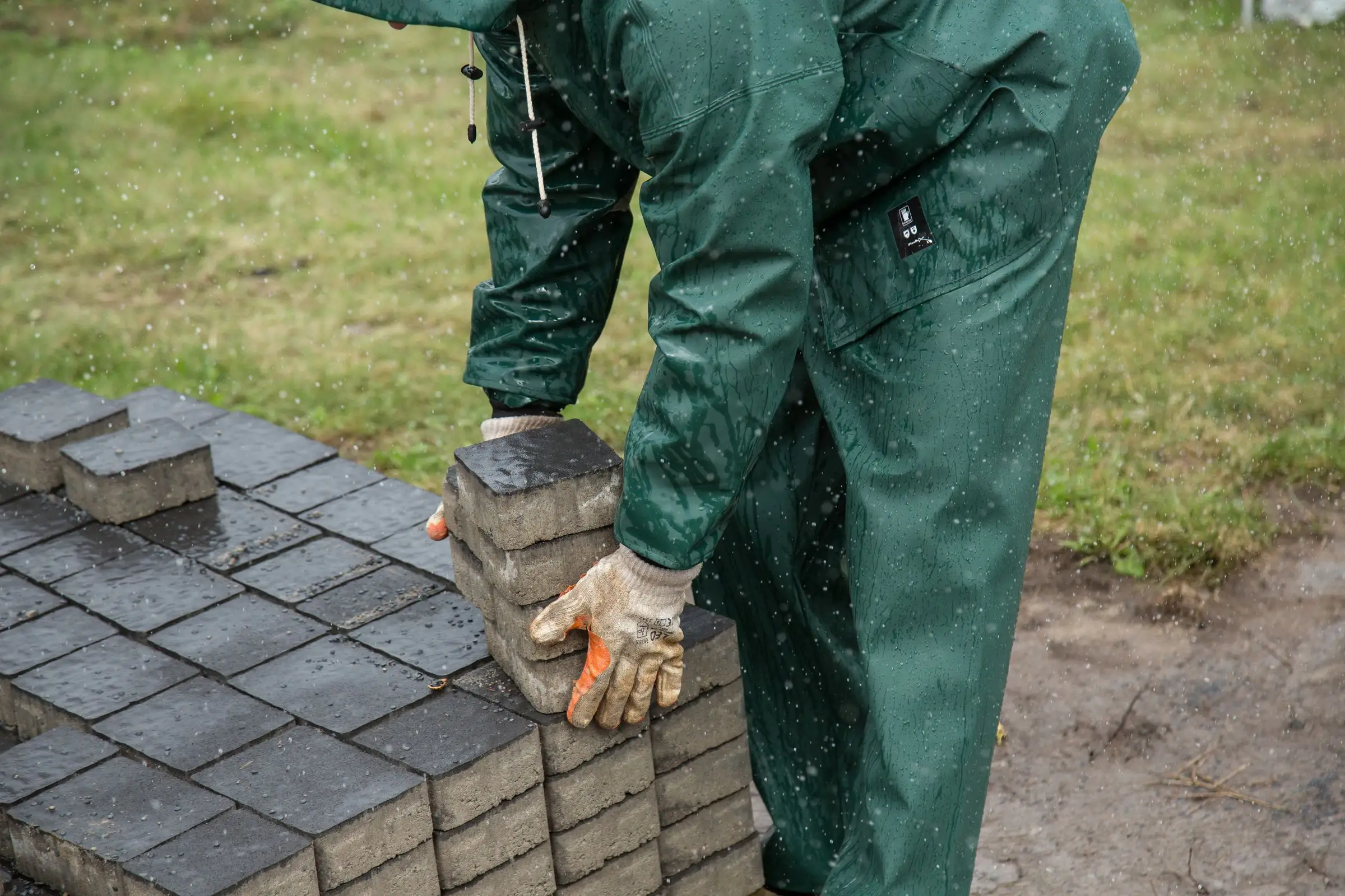 Pose de pavés sur un lit de sable sous la pluie