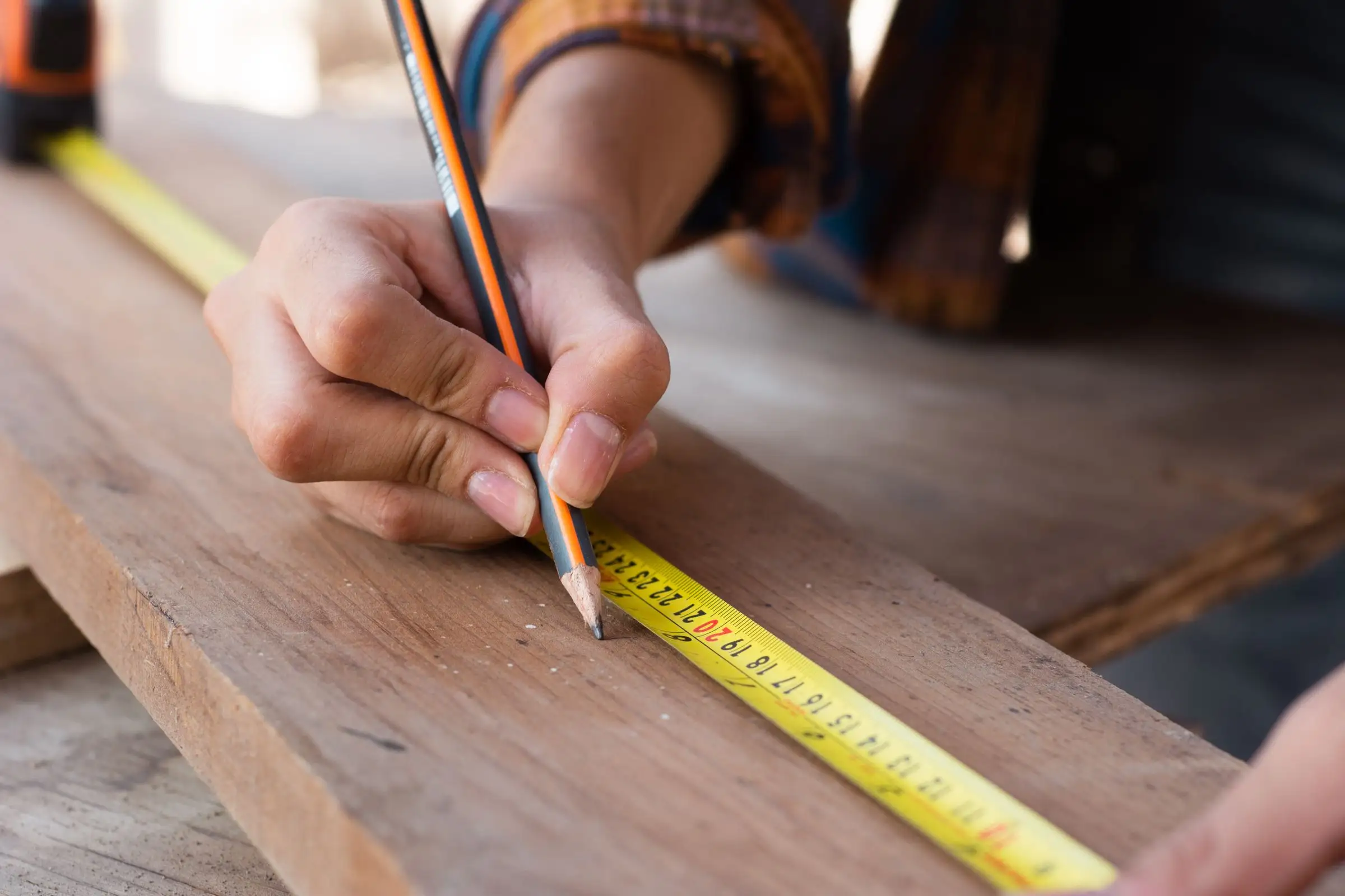 Hands measuring with a steel tape and marking the line with a pencil