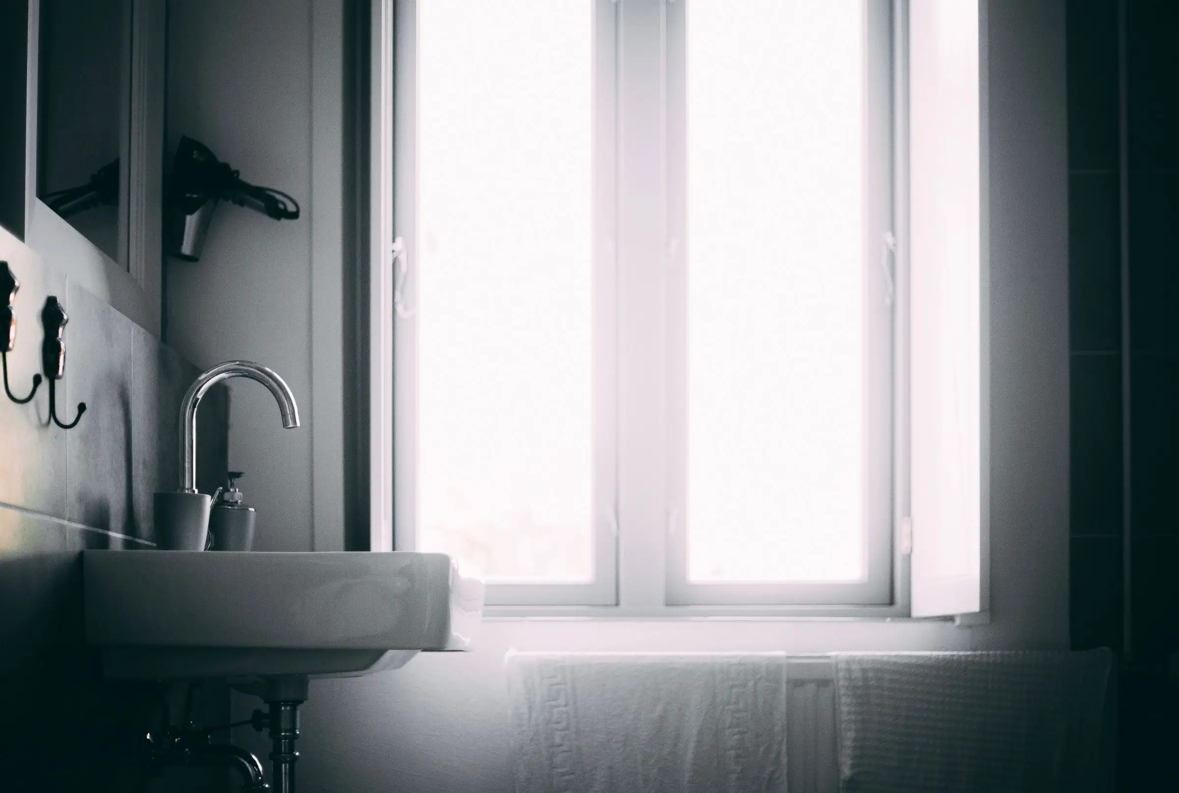 Minimal bathroom sink and faucet lit by daylight from one side