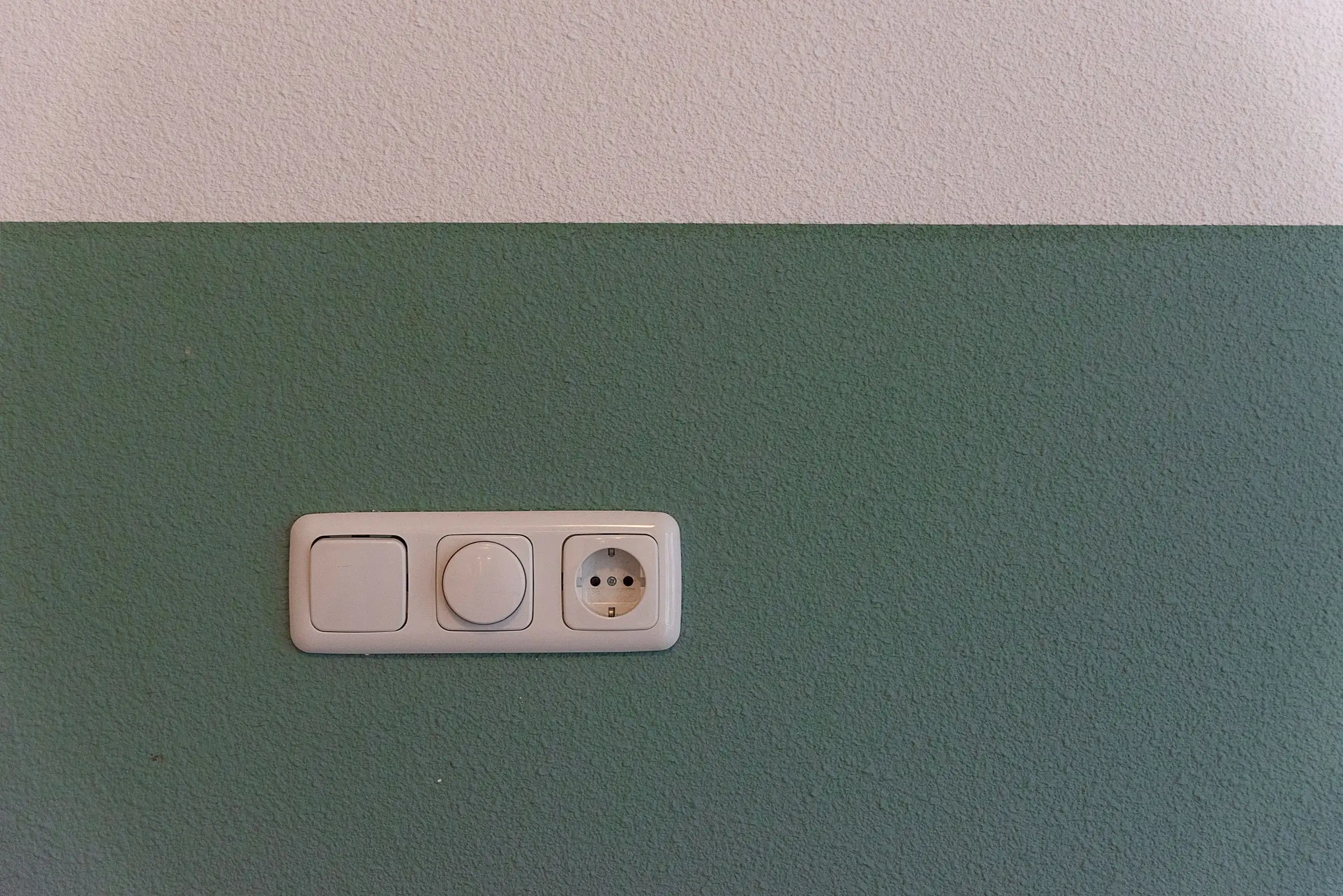 A single outlet and switch on a plain painted wall