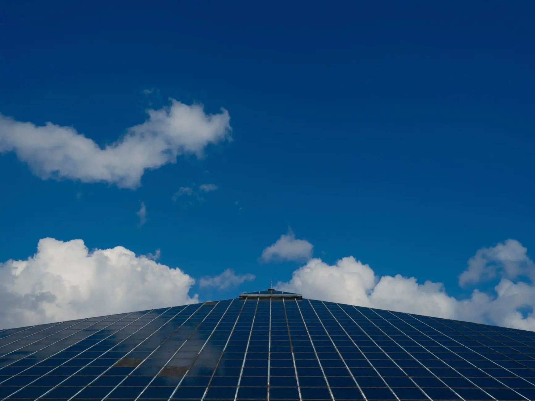 Rows of solar cells sweeping toward a blue sky stacked with clouds