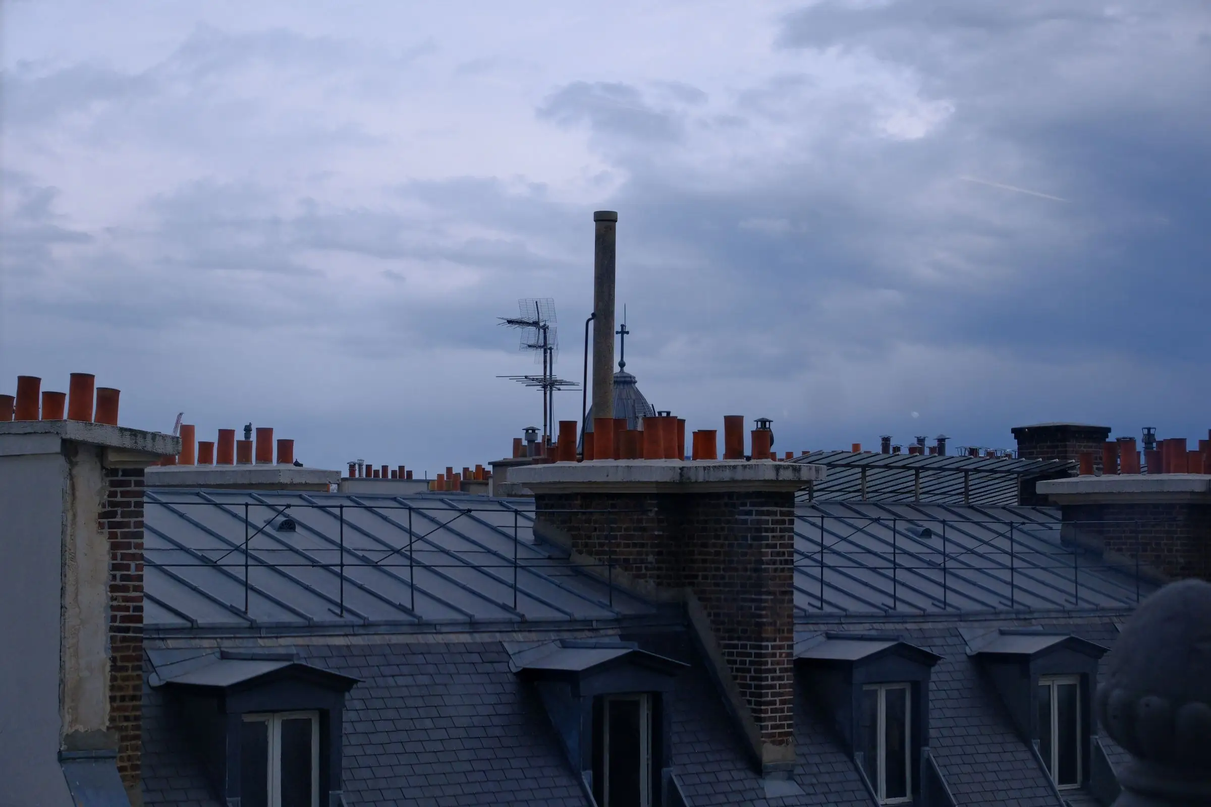 Toits de zinc et cheminées parisiennes au crépuscule