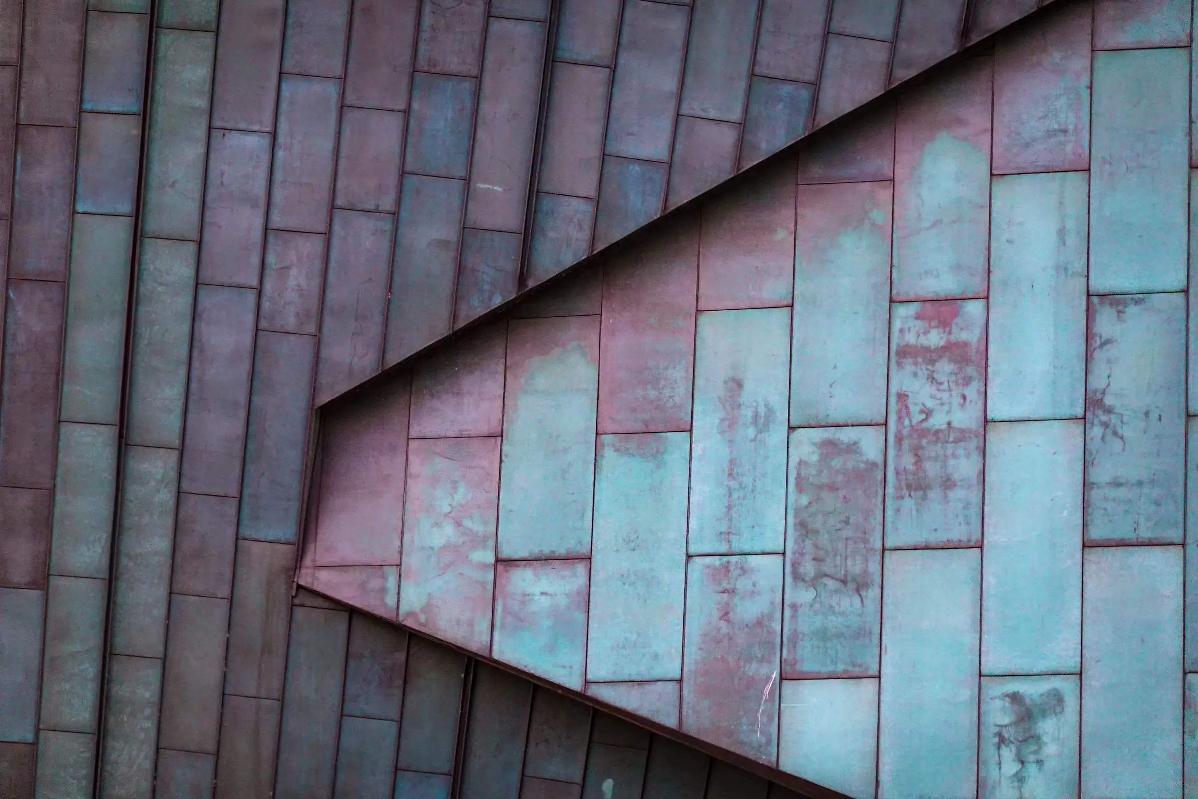 Weathered standing-seam metal roof panels meeting along a steep ridge