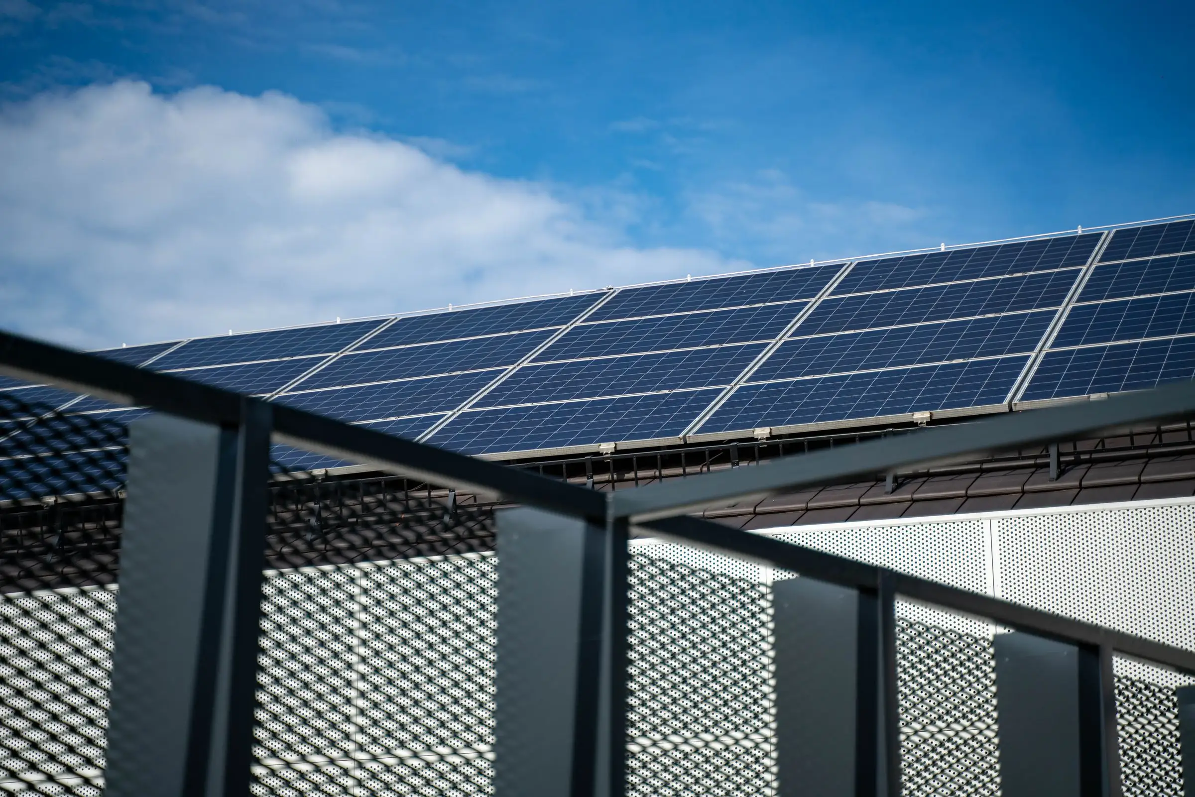 Rows of solar panels on a house roof, raking away against a clear sky