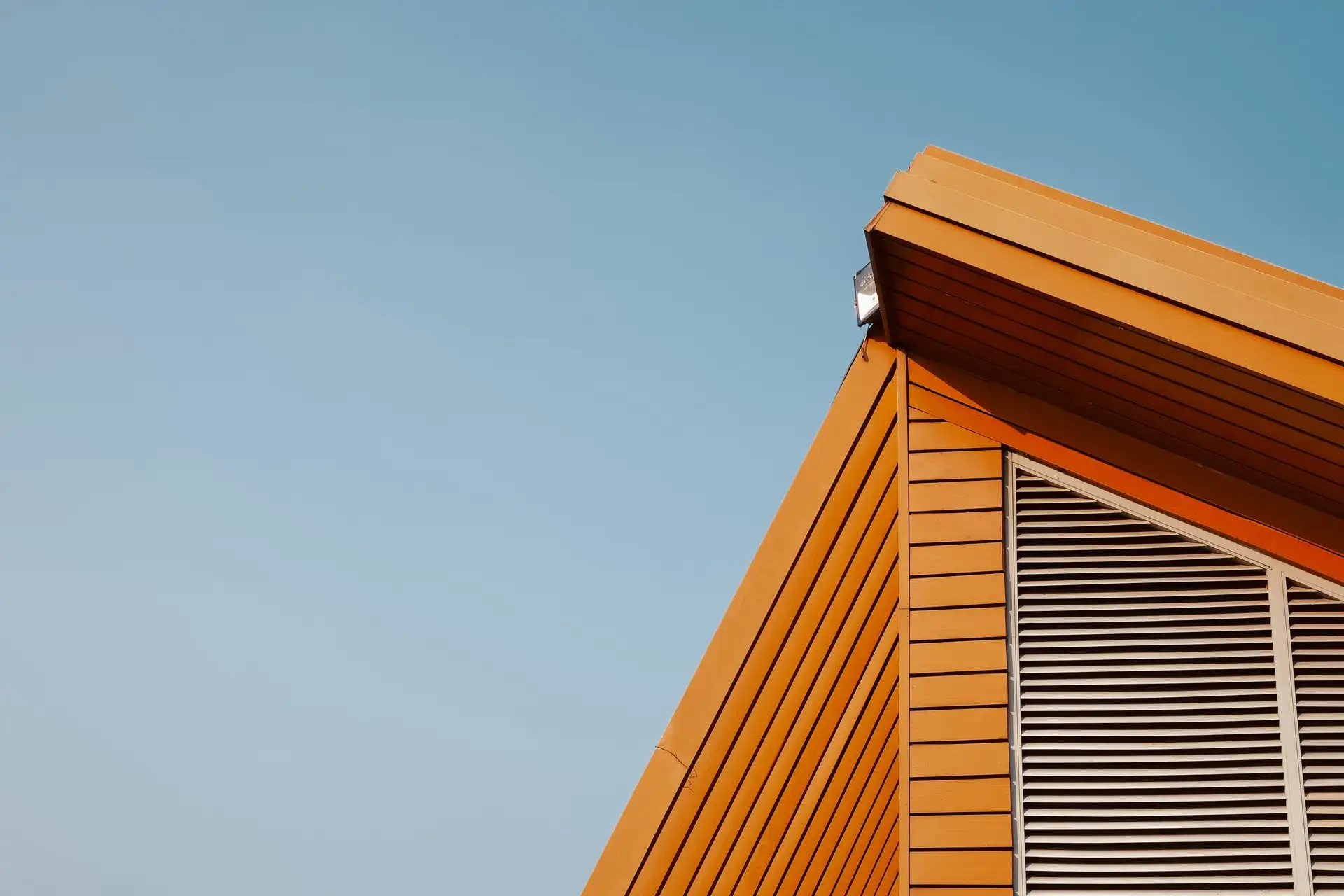 Deep roof overhang and gable end cutting across a pale sky
