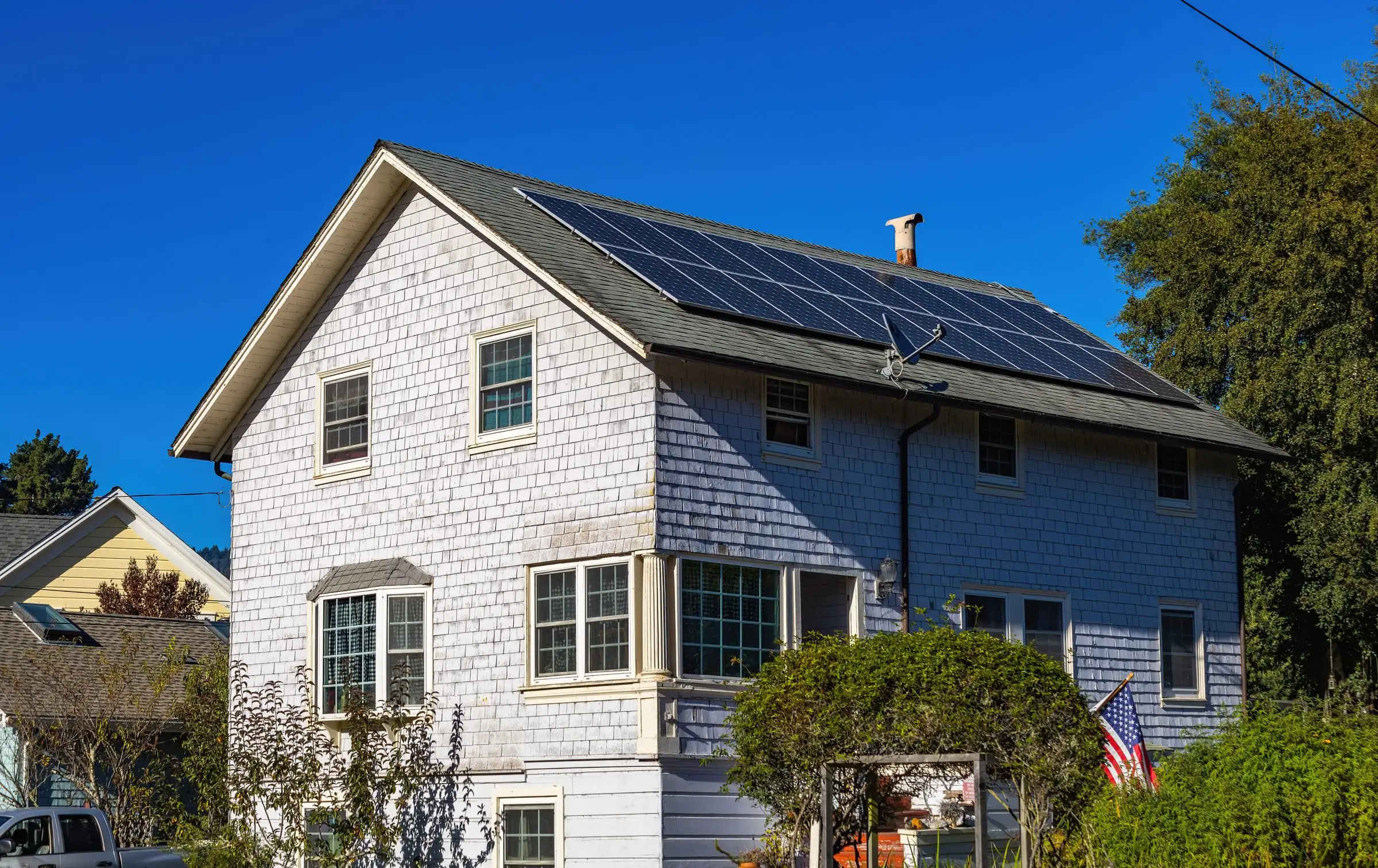 Two-story house carrying a full roof array under a clear sky