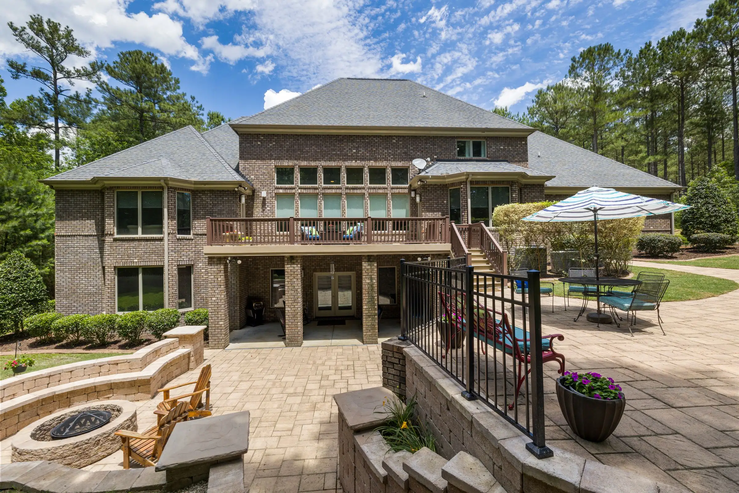Brick house with a paved terrace, a fire pit and planting beds around it