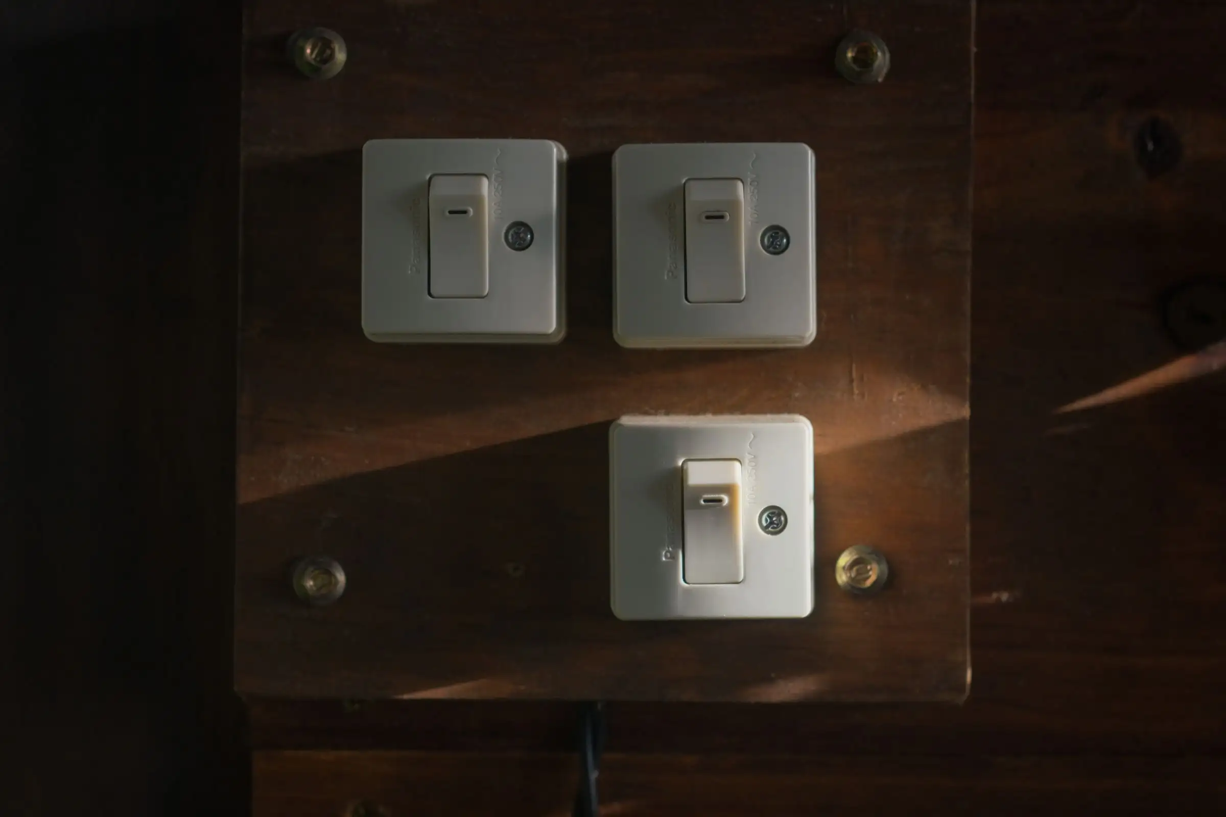 Old toggle switches on a wooden panel in low light