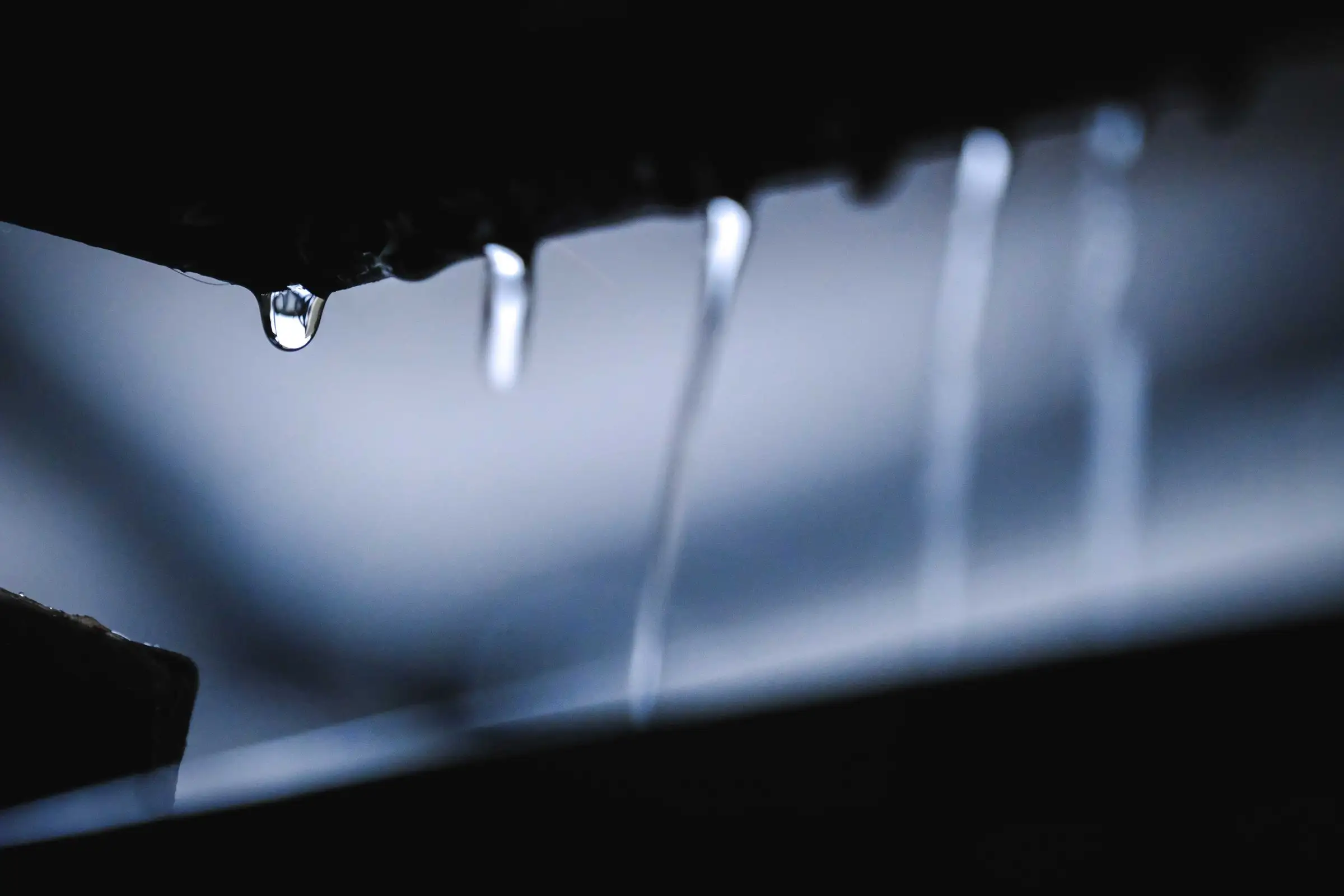 Water running and dripping down a dark surface