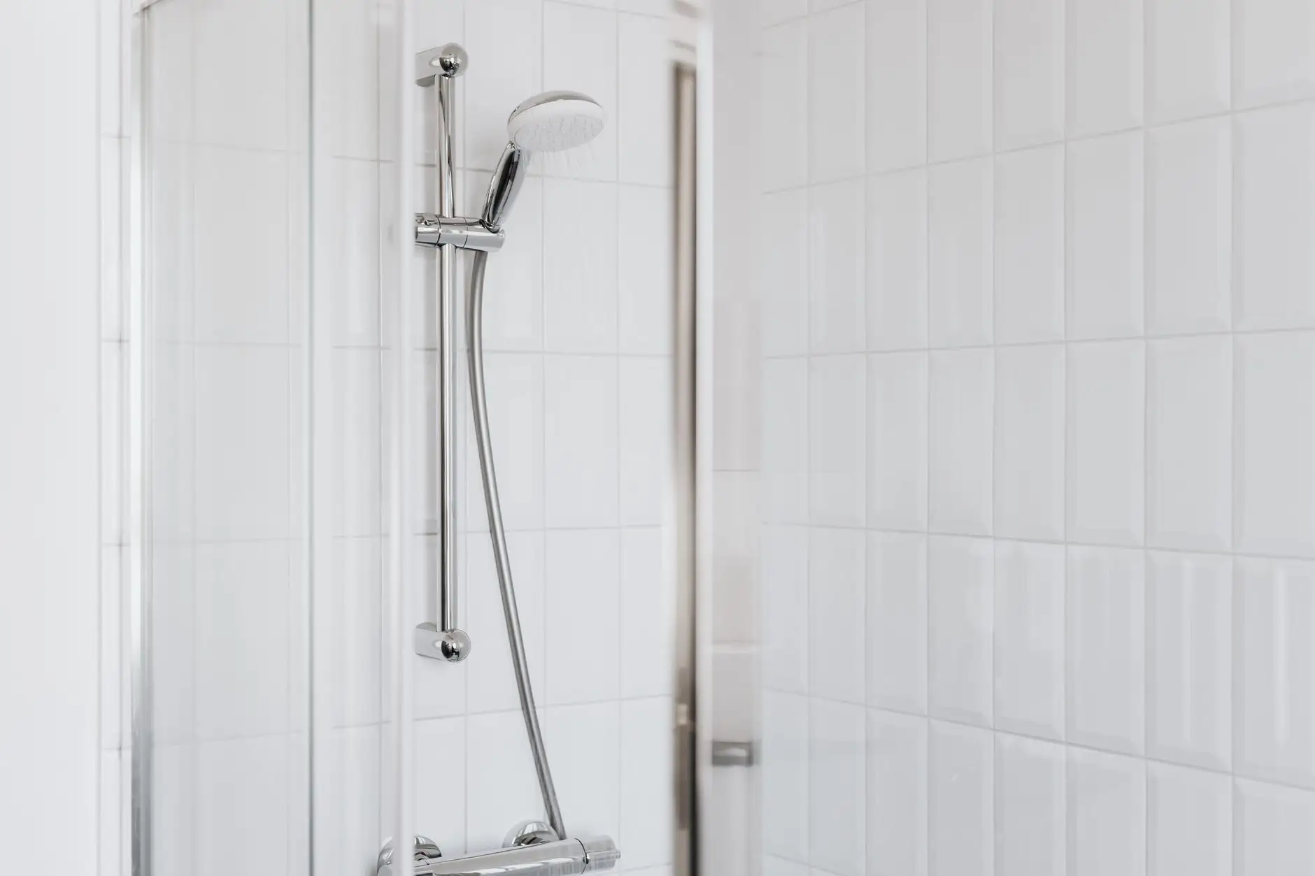 Chrome shower rail and head against white subway tile
