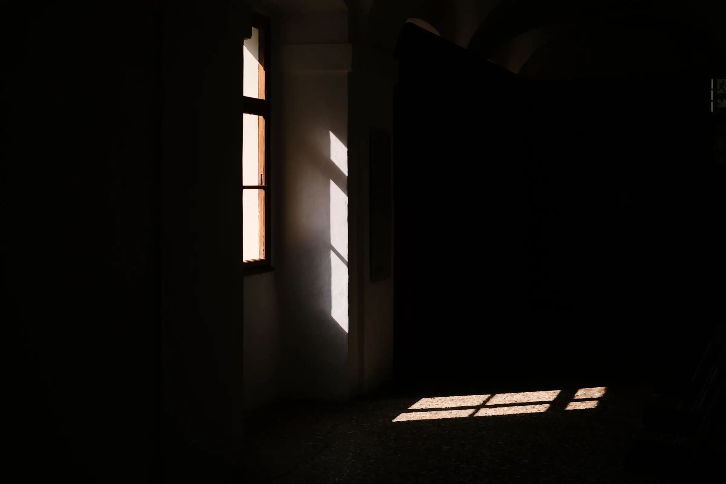 Daylight cutting through a window into a dark room, throwing the frame across the floor