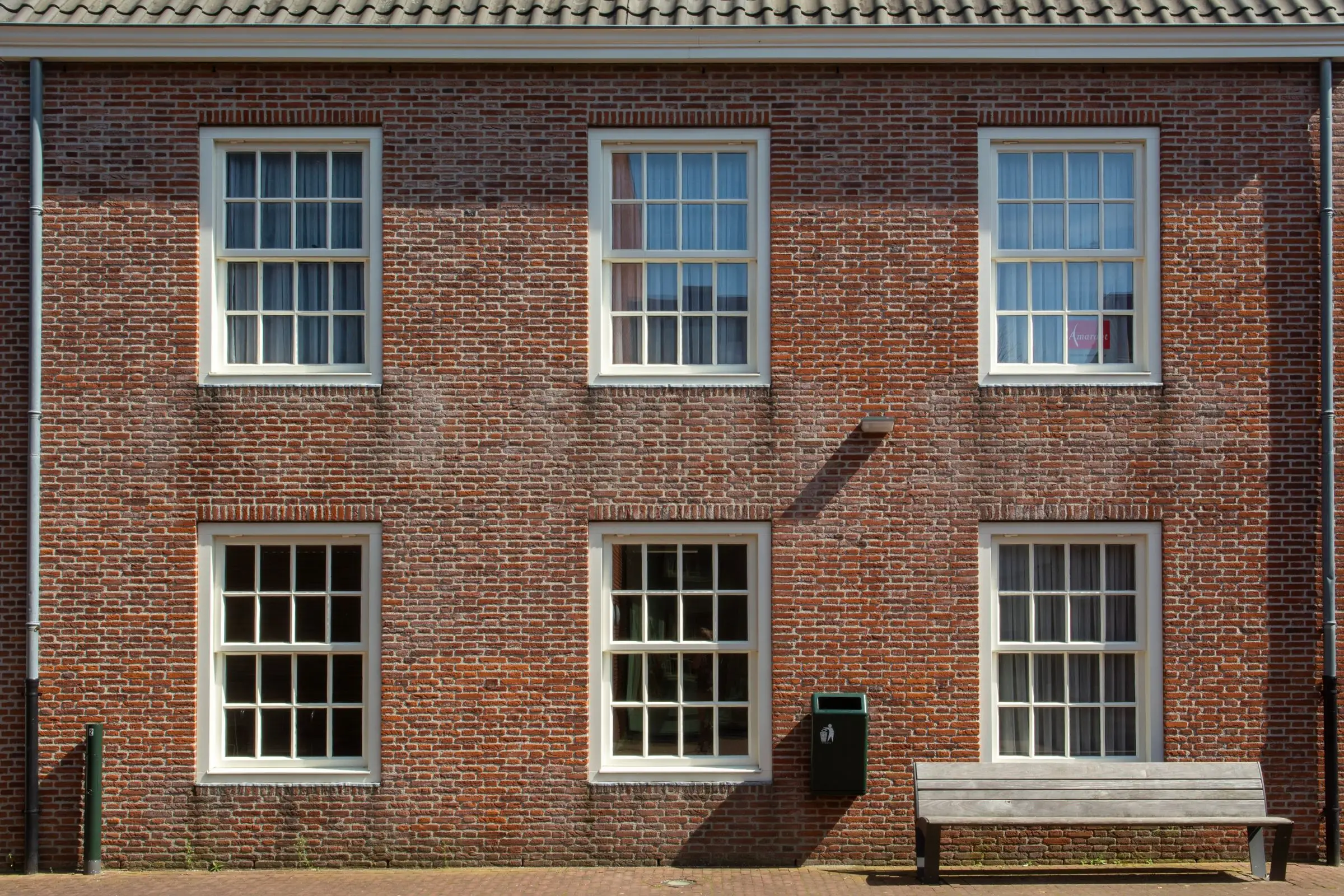 Six white sash windows set in a plain brick facade, three above three